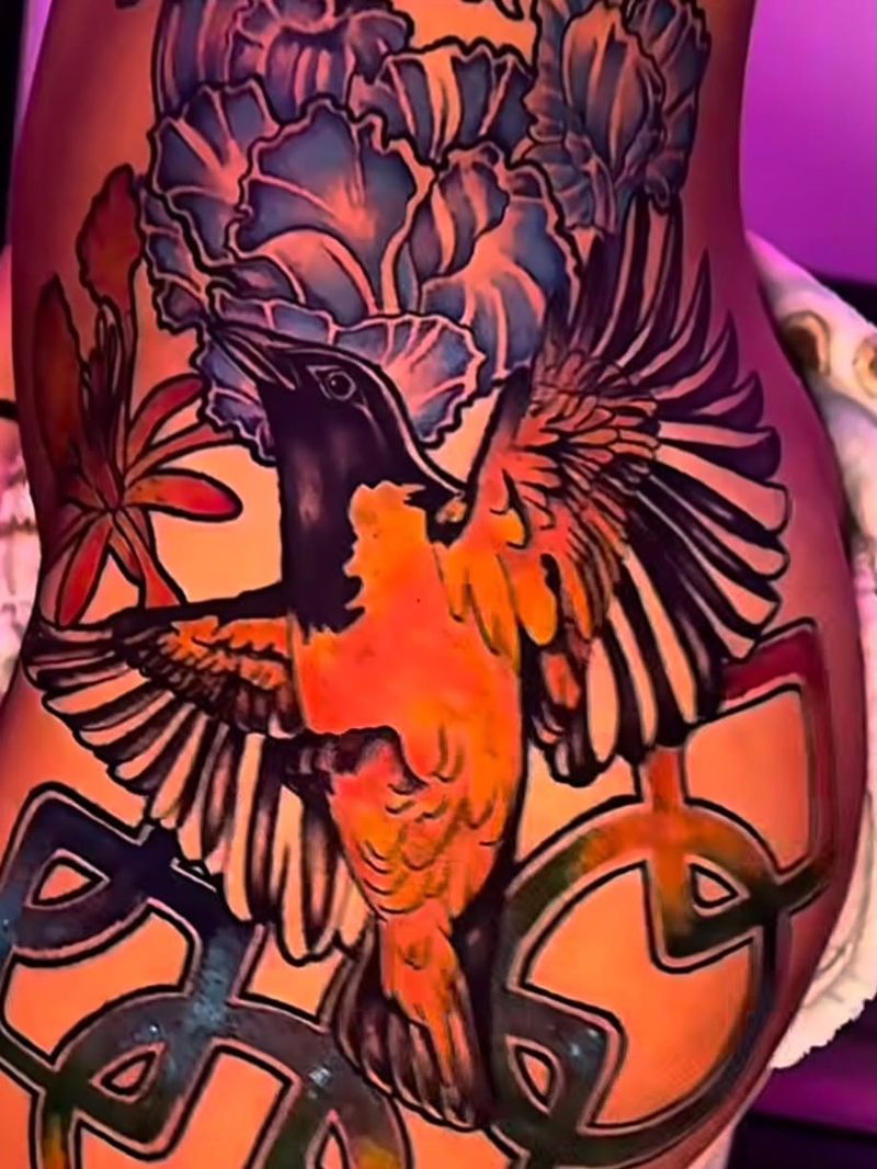 Color tattoo of a hummingbird with spread wings beneath blue and purple peony flowers, above interlocking chain links.